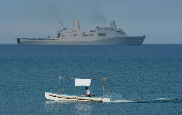 A Filipino fisherman passes a USS Green Bay during a landing exercise in the South China Sea. (Photo by TED ALJIBE/AFP/Getty Images)