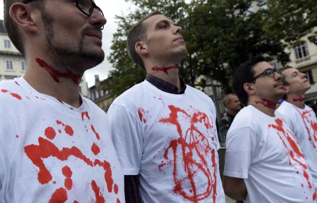 French far-right Front National (National Front) party activists with fake blood smeared on their throats and t-shirts look on during a rally to protest against the creation of a temporary slaughterhouse to provide a slaughtering facility in accordance with Islamic laws, to deal with increased demand during the Muslim celebration of the Eid al-Adha starting next week on September 18, 2015, in Saint-Etienne, central France. The Islamic festival of Eid al-Adha, or the Feast of Sacrifice, marks the end of the pilgrimage to Mecca and is celebrated in remembrance of Abraham's readiness to sacrifice his son to God. AFP PHOTO / PHILIPPE DESMAZES (Photo credit should read PHILIPPE DESMAZES/AFP/Getty Images)