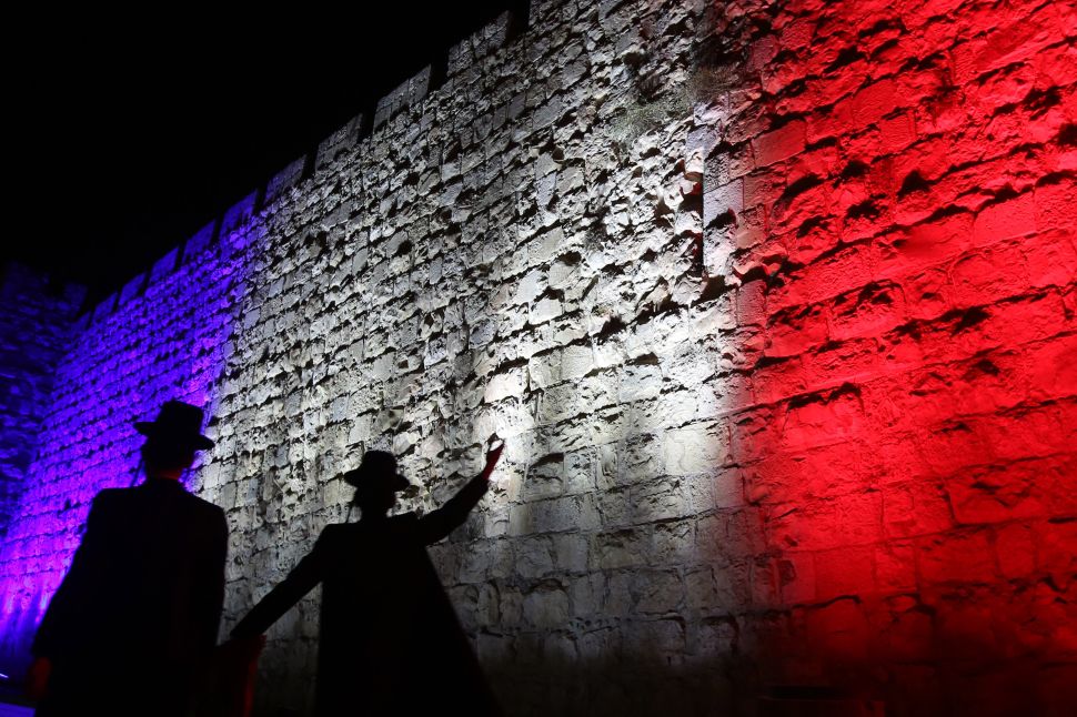 Israeli Jews walk past Jerusalem's Old City Ottoman Walls illuminated in red, white and blue, the colors of the French flag, in Jerusalem on November 15, 2015 in solidarity with France and the attacks in Paris. (GALI TIBBON/AFP/Getty Images)