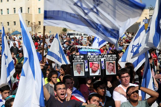 Israeli students, from the Israeli settlement of Kiryat Arba in the occupied West Bank, wave their national flags and hold up pictures of Israeli victims from recent Palestinian attacks, during a protest outside Israeli Prime Minister Benjamin Netanyahu office in Jerusalem on November 22, 2015, to demand more security on West Bank roads. AFP PHOTO/GALI TIBBON (Photo credit should read GALI TIBBON/AFP/Getty Images)