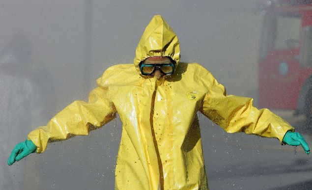 COLMA, CA - FEBRUARY 1: A man wearing a hazardous materials suit walks through a decontamination shower during a weapons of mass destruction training workshop February 1, 2005 in Colma, California. Representatives from several San Mateo County police and fire departments took part in the one day training to prepare for a chemical or biological attack. (Photo by Justin Sullivan/Getty Images)