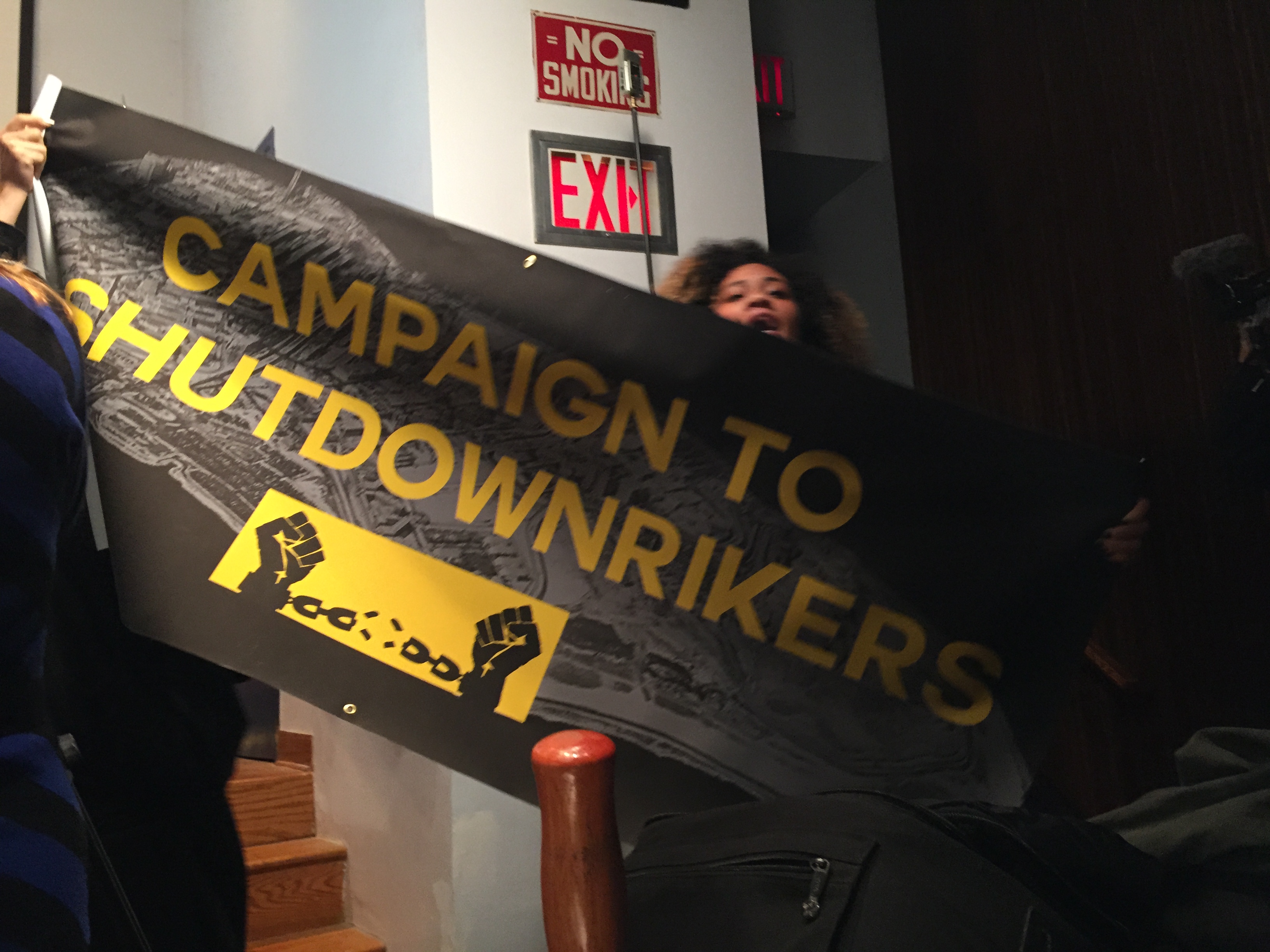 A woman holds up a banner calling for Rikers Island to be shut down. (Photo: Jillian Jorgensen for Observer)