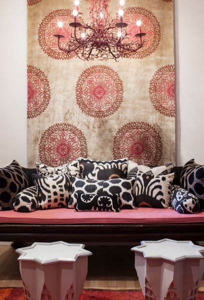 Madeline’s ikat pillows on a vintage opium bed in her showroom. On the wall: Madeline’s Gold Silk Gemma Tibetan Carpet (Photo: Andrea Chu for Observer).