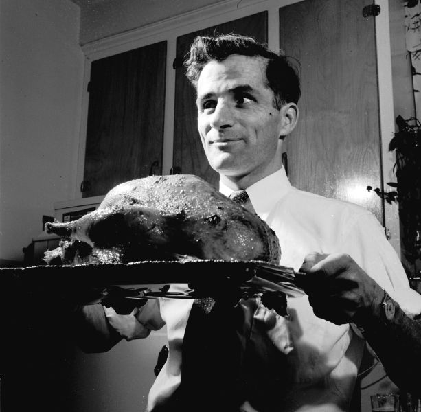 circa 1955: A man bringing a roast turkey to the table for a traditional Christmas dinner. (Photo by Evans/Three Lions/Getty Images)