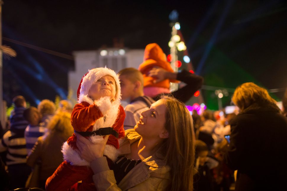 TEL AVIV, ISRAEL: An Israeli Arab woman holds a baby dressed as Santa Claus as locals prepare for Christmas in Jaffa, a mixed Jewish-Arab suburb of Tel Aviv, Israel. Christianity is one of the recognized religions in Israel and is practiced by more than 150 thousand Israeli citizens (about 2.1% of population). Some 127 thousand (80% of Christian residents) of Israel are Arab Christians. (Photo by Uriel Sinai/Getty Images)