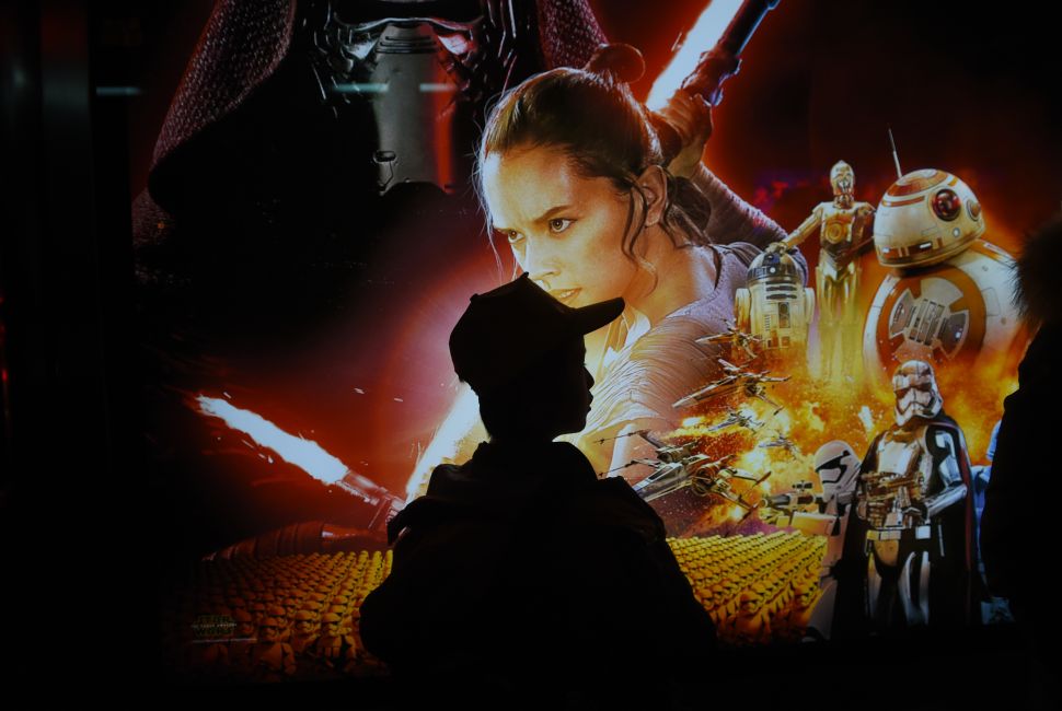A boy waits in front of a poster for "Star Wars: The Force Awakens" at a bus stop in Beijing. (Photo: GREG BAKER/Getty Images)
