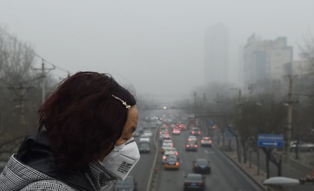 A woman wears a face mask on a heavily polluted day in Beijing on December 26, 2015. Thick smog continued a day after Beijing residents woke up to a white Christmas on December 25 with the sky obscured by thick toxic smog rather than snow. AFP PHOTO / GREG BAKER / AFP / GREG BAKER (Photo credit should read GREG BAKER/AFP/Getty Images)
