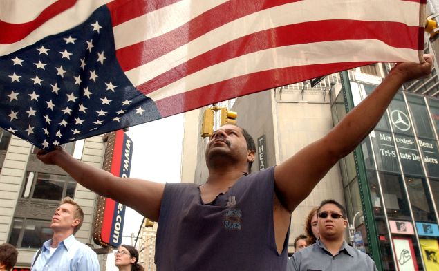 A man unfurls the American flag on the first anniversary of 9/11 (Photo: Justin Sullivan for Getty Images)