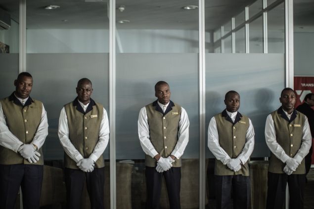 South African luxury Blue Train butlers waits for passengers to leave the Blue Train lounge ahead of a press train journey on September 8, 2015 in Pretoria, South Africa. South Africa transport giant Transnet began on September 8, a partnership with Africa's largest tourism, leisure and gaming group Sun International. Transnet chose Sun International as the winning bidder to develop and implement a marketing strategy for the Blue Train. AFP PHOTO/GIANLUIGI GUERCIA