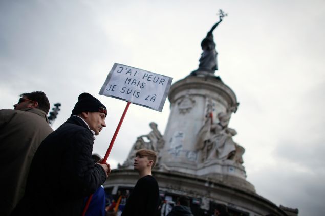 TOPSHOT - A man holding a placard reading "I am afraid but I am here" during a gathering on Place de la Republique (Republic square) on January 10, 2016 in Paris, as the city marks a year since 1.6 million people thronged the French capital in a show of unity after attacks on the Charlie Hebdo newspaper and a Jewish supermarket. Just as it was last year, the vast Place de la Republique is the focus of gatherings as people reiterate their support for freedom of expression and remember the other victims of what would become a year of jihadist outrages in France, culminating in the November 13 coordinated shootings and suicide bombings that killed 130 people and were claimed by the Islamic State (IS) group. AFP PHOTO / THOMAS SAMSON / AFP / THOMAS SAMSON (Photo credit should read THOMAS SAMSON/AFP/Getty Images)