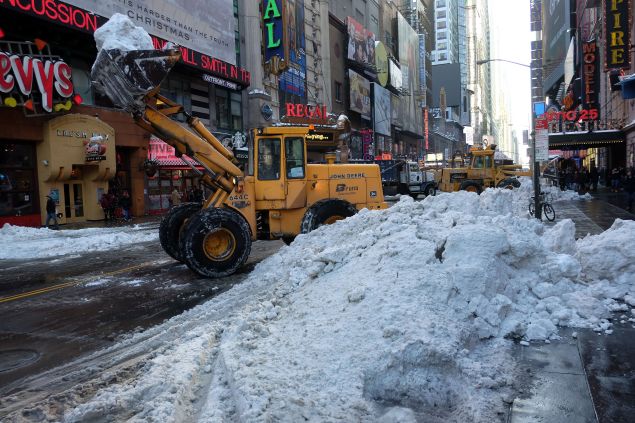 Department of Sanitation workers use bulldozers to clean pile of snow from the street in New York on January 25, 2016. The eastern US emerged wearily from a massive blizzard that dumped huge amounts of snow and killed at least 25 people, but Washington was still reeling, with government offices and schools to remain closed on Monday. / AFP / JEWEL SAMAD (Photo credit should read JEWEL SAMAD/AFP/Getty Images)