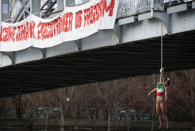 A FEMEN activist hangs from a mock noose during a protest in Paris against the visit of the Iranian president. (Photo: Joel Saget/AFP/Getty Images)