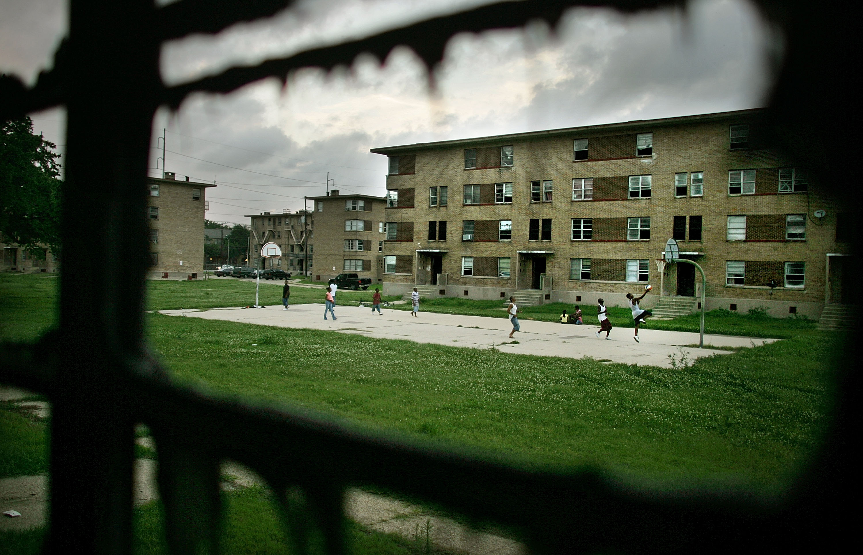 NEW ORLEANS - JUNE 07: B.W. Cooper housing project residents play basketball in front of storm damaged apartments in the complex June 7, 2007 in New Orleans, Louisiana. Before Hurricane Katrina, B.W. Cooper held about 1,000 families and was the city's largest housing project, but it is now more than 80 percent empty. Around 10,000 public housing residents in New Orleans have been unable to return to their apartments because of storm damage. The U.S. Department of Housing and Urban Development plans to tear down B.W. Cooper and other major New Orleans housing projects and replace them with mixed income developments. (Photo by Mario Tama/Getty Images)