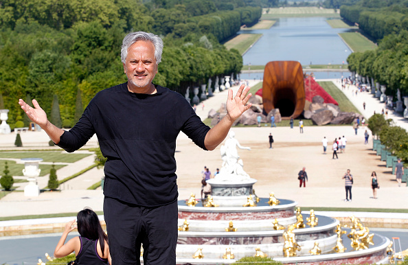 VERSAILLES, FRANCE - JUNE 05: British contemporary artist of Indian origin Anish Kapoor poses in front of his artwork named 'Dirty Corner' at the opening of his exhibition of his works in the gardens of the Chateau de Versailles on June 5, 2015, in Versailles, France. This exhibition takes place from June 9 until November 01, 2015 in the gardens of the 'Chateau de Versailles'. 