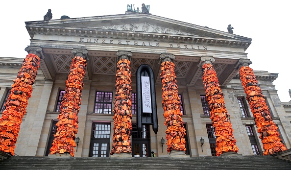 BERLIN, GERMANY - FEBRUARY 14: An art installation by Chinese artist Ai Weiwei showcases thousands of used life vests by refugees from the Greek island of Lesbos, on February 14, 2016 in Berlin, Germany. The orange vests are wrapped around the pillars of the city's Konzerthaus to highlight the plight of refugees trying to reach Europe.