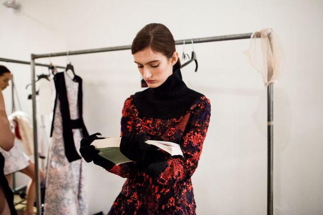 A model catches up on her reading backstage