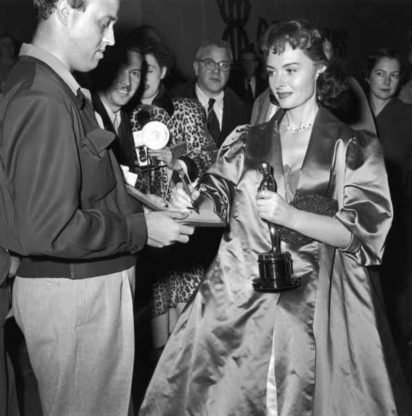 American actor Donna Reed (1921 - 1986) signs an autograph while holding her Oscar trophy at the Academy Awards, Los Angeles, California, March 25, 1954. =
