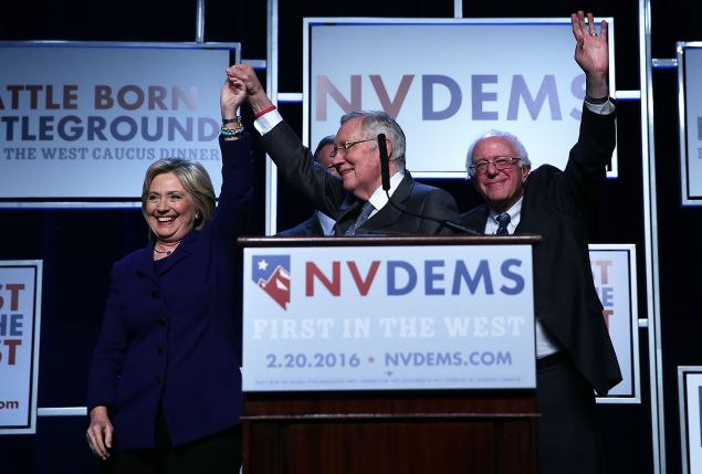 Democratic Presidential candidates Hillary Clinton and Sen. Bernie Sanders on stage with Senate Minority Leader Harry Reid prior to the Battle Born/Battleground First in the West Caucus Dinner at the MGM Grand January 6, 2016 in Las Vegas, Nevada. The three candidates continue to campaign prior to the Nevada Democratic caucus, which will take place on February 20, 2016.