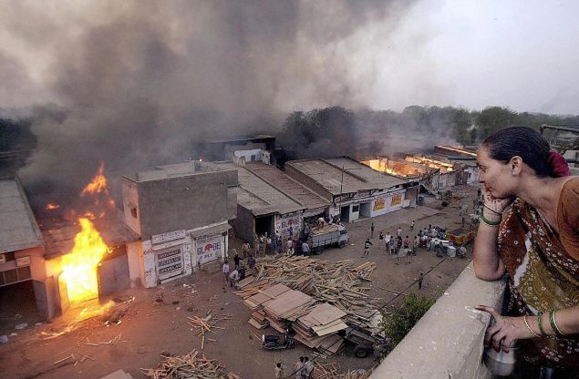 AHMEDABAD, INDIA: (FILES) This picture taken 28 February 2002 shows Ahmedabad resident Jaiwantiben watching a wood market burning after it was set ablaze by Muslims that fled the Lathi bazar area in Ahmedabad. SEBASTIAN D'SOUZA/AFP/Getty Images)