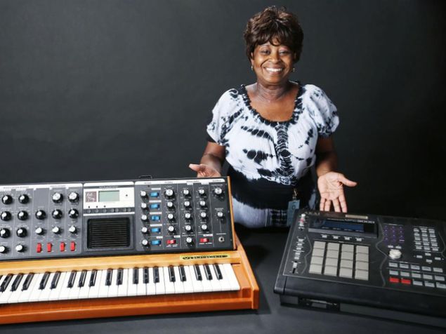 J Dilla's mother, Maureen Yancey, a.k.a. Ma Dukes, poses with Dilla's custom-made Mini Moog Voyager Synth and Akai MIDI Production Center 3000, which were donated to the Smithsonian. (Photo: Courtesy of J Dilla.)