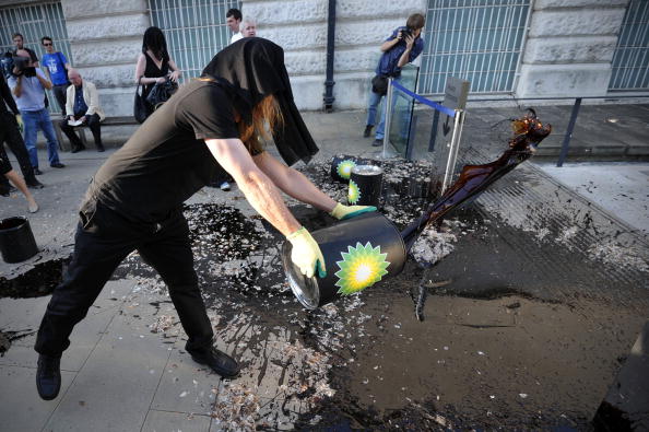 A protester belonging to a group of artists calling themselves 'The Good Crude Britannia', who want the Tate to cut its ties with British Petroleum (BP), throws a substance thought to be molasses on the floor outside, the Tate Britain on June 28, 2010, as the gallery holds its summer party.