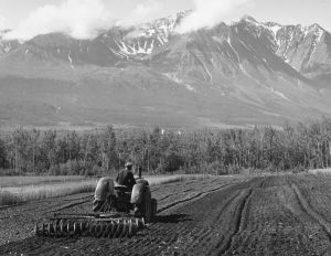 A tractor ploughs the land at the foot of a mountain in western Canada, 1950.