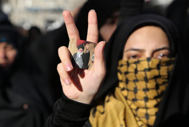 An Iranian student shows flashes the sign of victory holding a portrait of Iran's Supreme Leader Ayatollah Ali Khamenei during a demonstration on February 18, 2015, near the Swiss embassy in Tehran, in solidarity with the three Muslim American students murdered last week in the North Carolina university town of Chapel Hill. The three victims were shot dead on February 10 in their home in North Carolina, allegedly by neighbour Craig Stephen Hicks, 46, whose Facebook page espoused anti-religious views.