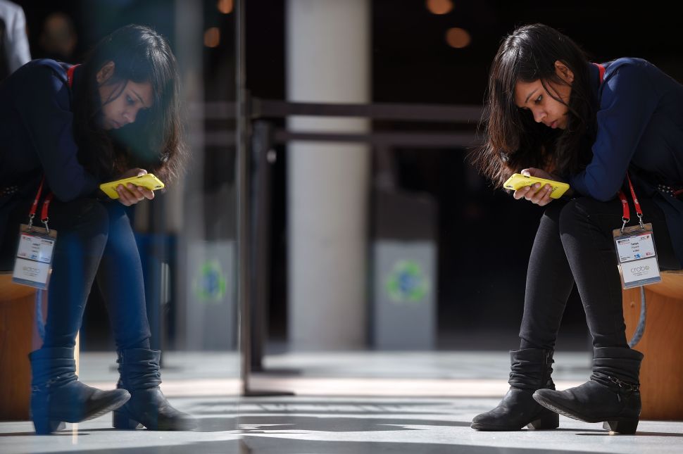 A visitor uses a mobile phone on the third day of the Mobile World Congress in Barcelona on February 24, 2016. The world's biggest mobile fair Nobile World Congress (MWC), is held from February 22 to February 25. / AFP / LLUIS GENE