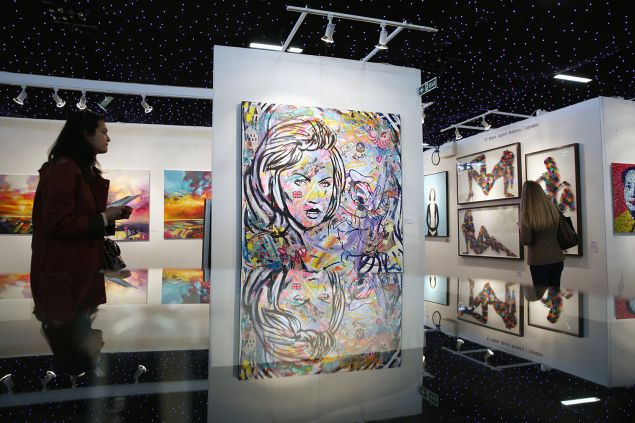 Members of the public walk through gallery spaces at the 'Affordable Art Fair' in Battersea Park on March 11, 2016 in London.