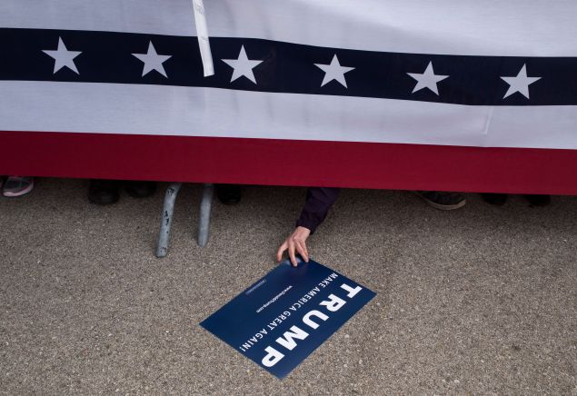 An attendee reaches under the security rail to reach for a campaign sign that was dropped at a campaign rally for Republican Presidential candidate Donald Trump on March 12, 2016 in Vandailia, Ohio. Today was the first rally after violence broke out in a Trump Rally in Chicago yesterday which canceled the rally. 