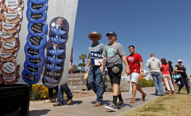 Supporters of Republican presidential candidate Donald Trump walk past campaign buttons during a campaign rally at Fountain Park on March 19, 2016 in Fountain Hills, Arizona. Trump visits Arizona for the second time in three months as he looks to gain the GOP nomination for President.