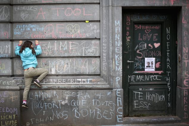 A young girl climbs a wall to chalk a message of support on the the Bourse De Brussels building in the Place de la Bourse following yesterday's terrorists attacks on March 23, 2016 in Brussels, Belgium. Belgium is observing three days of national mourning after 34 people were killed in a twin suicide blast at Zaventem Airport and a further bomb attack at Maelbeek Metro Station. Two brothers are thought to have carried out the airport attack and an international manhunt is underway for a third suspect. The attacks come just days after a key suspect in the Paris attacks, Salah Abdeslam, was captured in Brussels.