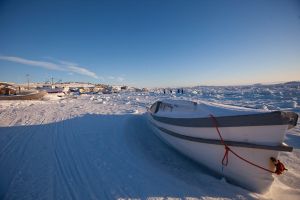 A boat sits along the frozen shoreline in Iqaluit, Canada.