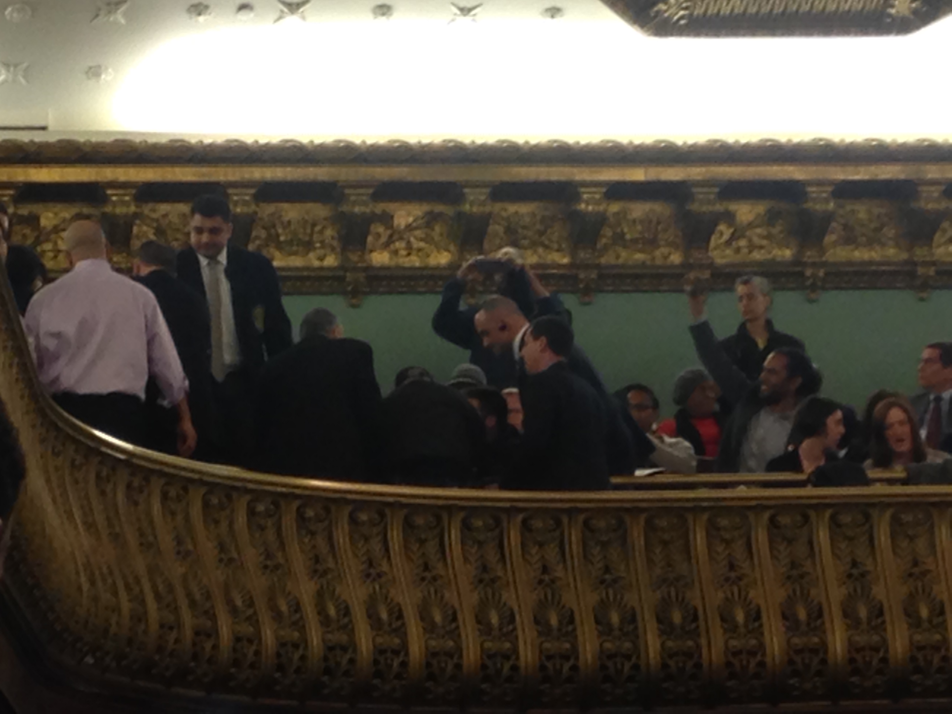 Council security and police try to pry protesters from their seats in the balcony.