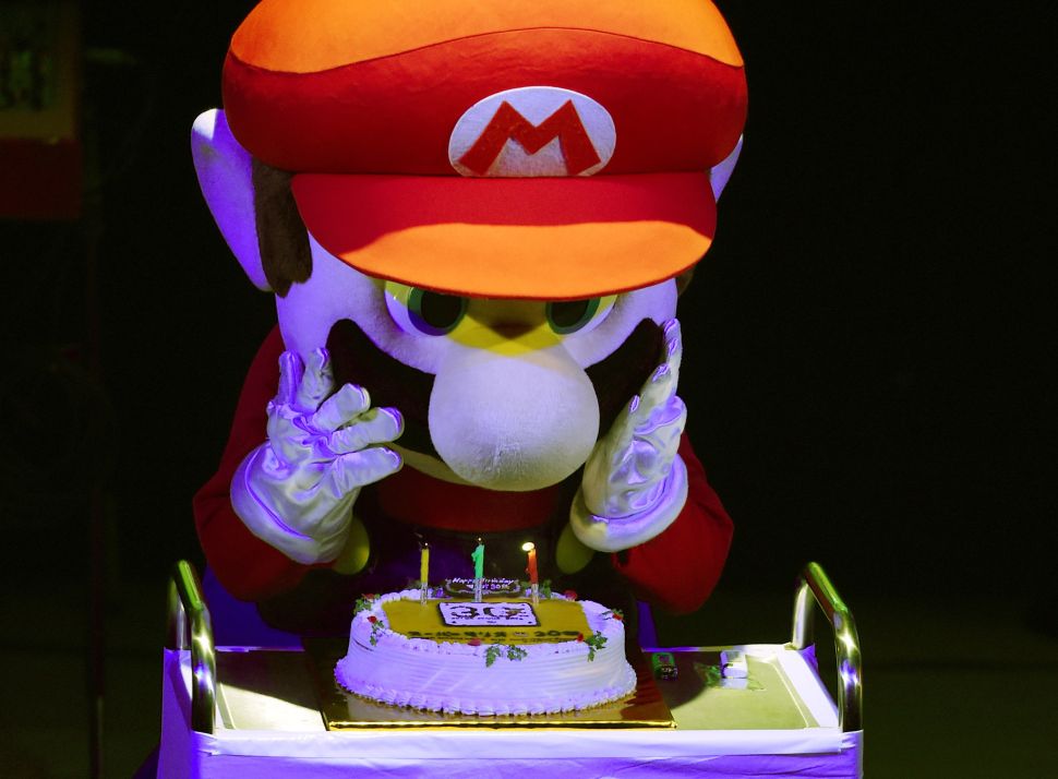 "Super Mario" blows out the candles on a cake during celebrations and a live performance of the most well-known Mario music to mark the game's 30th anniversary in Tokyo on September 13, 2015. Nintendo celebrated the 30th anniversary of Super Mario, one of the best-known characters in video game history, at the event in Tokyo where artists played his theme music to fans dressed up as the hyperactive plumber. AFP PHOTO / TOSHIFUMI KITAMURA 