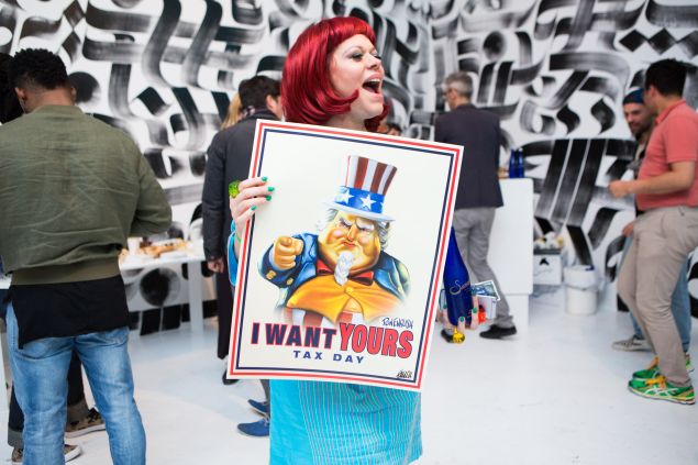 Lady Miss Kier holding a poster designed by Ron English. In the background, a mural by Roastarr.