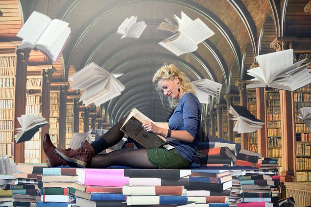 FRANKFURT AM MAIN, GERMANY - OCTOBER 09: A woman pose for a photo in front of photowall with motiv of a phantasy library at the 2013 Frankfurt Book Fair on October 9, 2013 in Frankfurt, Germany. This year's fair will be open to the public from October 9-13 and the official partner nation is Brazil.