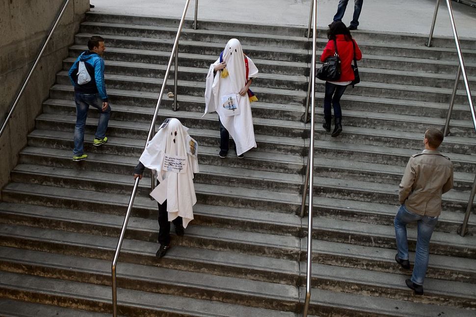 Two FC Basel fans disguised as ghosts leave St. Jakob Stadium prior to the UEFA Europa League quarter-final first leg football match FC Basel vs Valencia CF on April 3, 2014 in Basel. Swiss club FC Basel must play their Europa League quarter-final first leg clash against Valencia behind closed doors after being punished for the violent behavior of their fans. UEFA also fined FC Basel 107,000 euros ($147,500) after objects, including cigarette lighters, were thrown on to the pitch in their last-16 clash against Salzburg last week with the referee halting the game for 10 minutes. AFP PHOTO / FABRICE COFFRINI