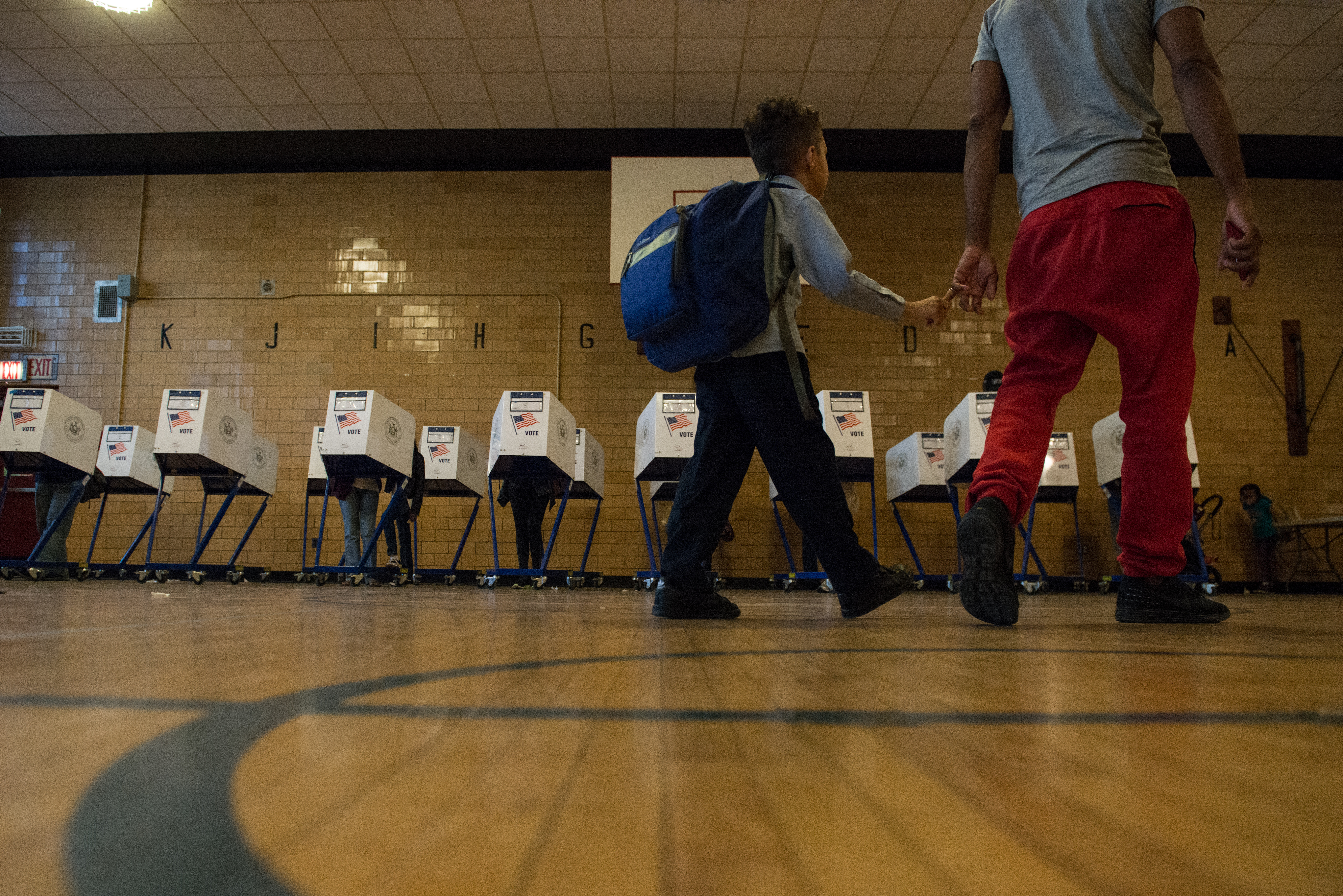 A man with his son walk past voting booths at Public School 22 in Brooklyn on Tuesday.