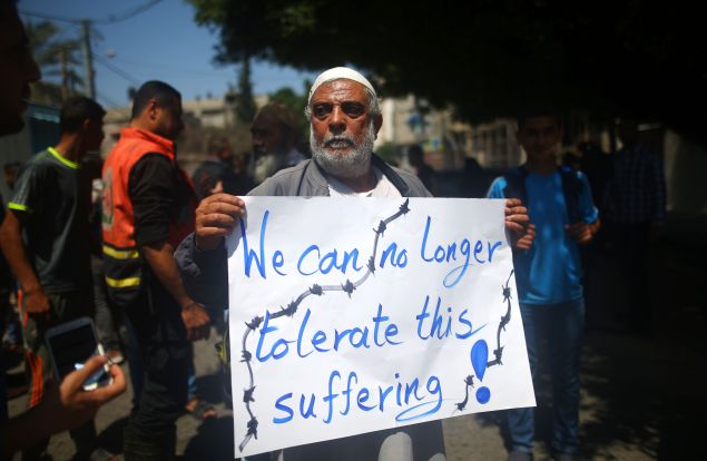  A Palestinian whose home was destroyed during 50-day war between Israel and Hamas militants in the summer of 2014 holds a banner during a protest in front of United Nations Development Programme (UNDP) headquarters, in Gaza City on April 20, 2016, against the ban of private imports of cement to the Palestinian enclave. / AFP / MOHAMMED ABED 