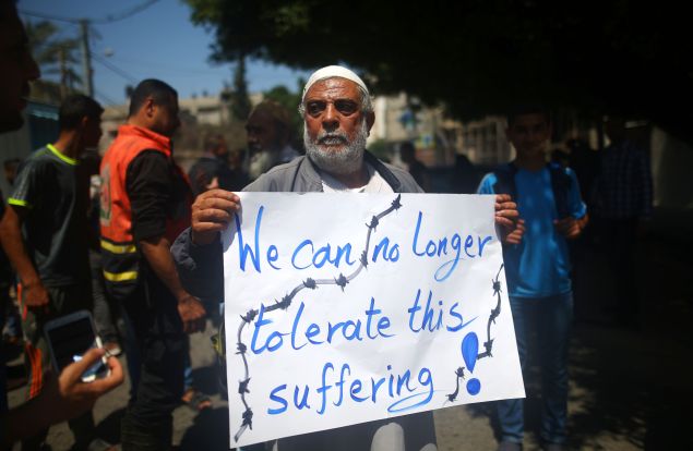 A Palestinian whose home was destroyed during 50-day war between Israel and Hamas militants in the summer of 2014 holds a banner during a protest in front of United Nations Development Programme (UNDP) headquarters, in Gaza City on April 20, 2016, against the ban of private imports of cement to the Palestinian enclave. / AFP / MOHAMMED ABED