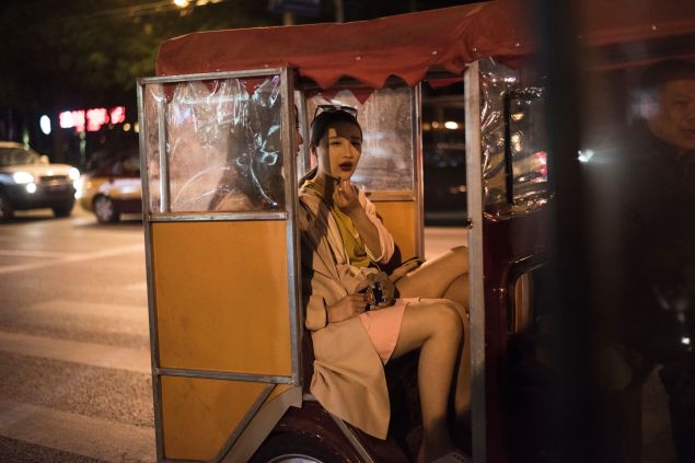 Two ladies take a tricycle in the streets of Beijing on April 20, 2016.