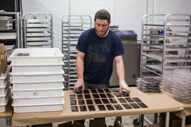 A worker at Rakka Chocolate factory in Red Hook, Brooklyn, lays out freshly made chocolate bars. 5/24/2016 - Photo by Aaron Adler for The Commercial Observer