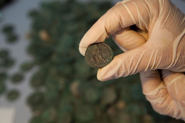 Roman era bronze coins are displayed at the archaeological museum in Sevilla on April 28, 2016 following their discovery during development works for pipelines and installations in the El Zaudine park in Tomares on the outskirts of Sevilla. Some 19 amphorae, nine of which were retrieved fragmented, containing around 600kg of bronze coins from the fourth century AD were found by employees using earth moving machinery in an underground space covered by bricks and ceramic filler. / AFP / Gogo Lobato
