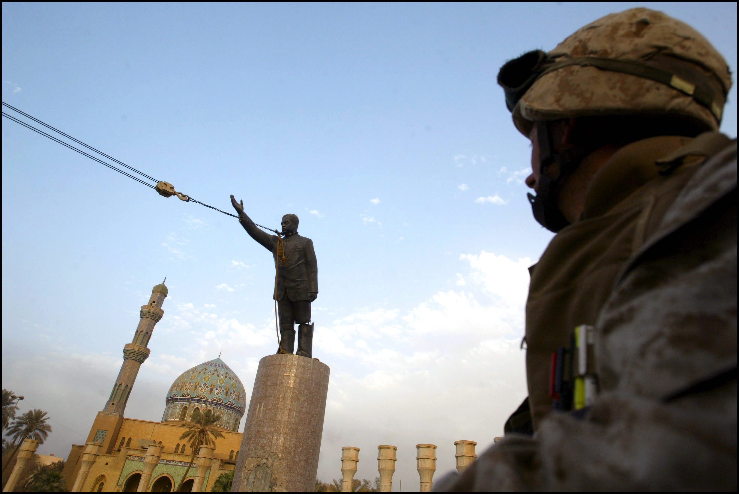 U.S. Marine watches as statue of Saddam Hussein topples in 2003.