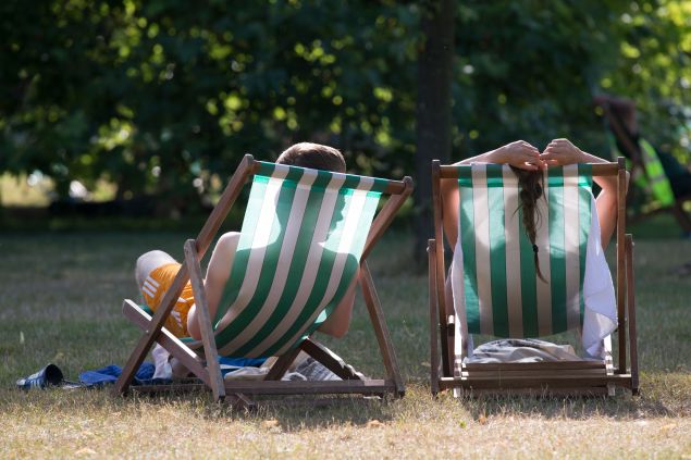 A couple relax on deckchairs in the warm weather in Hyde Park on July 18, 2014 in London, England.