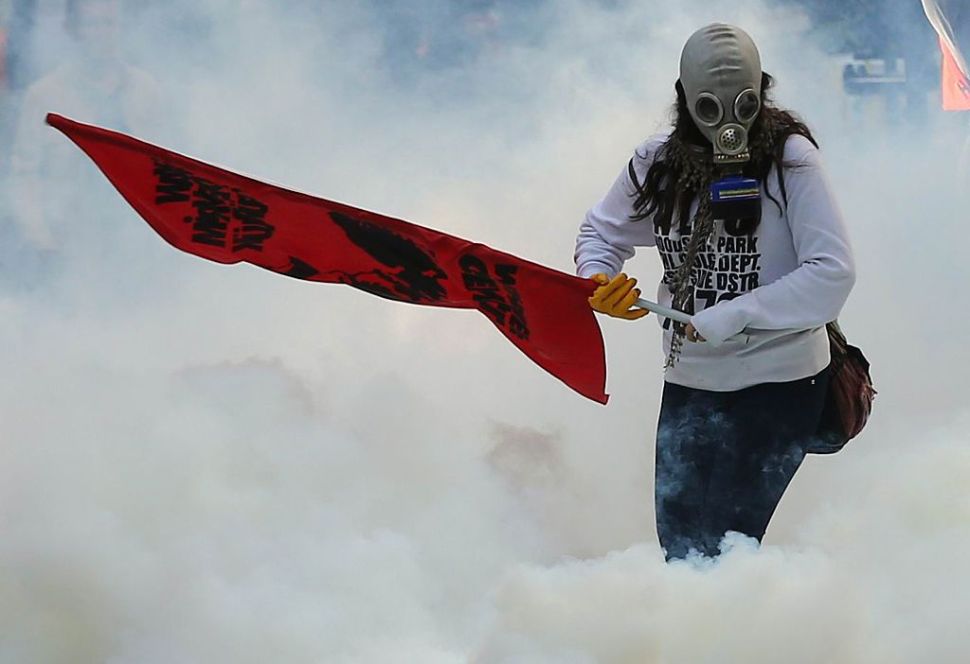 A person holds a flag as police uses tear gas and water cannon on October 7, 2014 in Ankara against demonstrators who protest against attacks launched by Islamic State insurgents targeting the Syrian city of Kobane and lack of action by the government. Fresh air strikes by the US-led coalition hit positions held by Islamic State jihadists in the southwest of the key Syrian border town of Ain al-Arab (Kobane), according to an AFP journalist just across the border in Turkey. The strikes came a day after the extremists pushed into Kobane, seizing three districts in the city's east after fierce street battles with its Kurdish defenders. AFP PHOTO/ADEM ALTAN