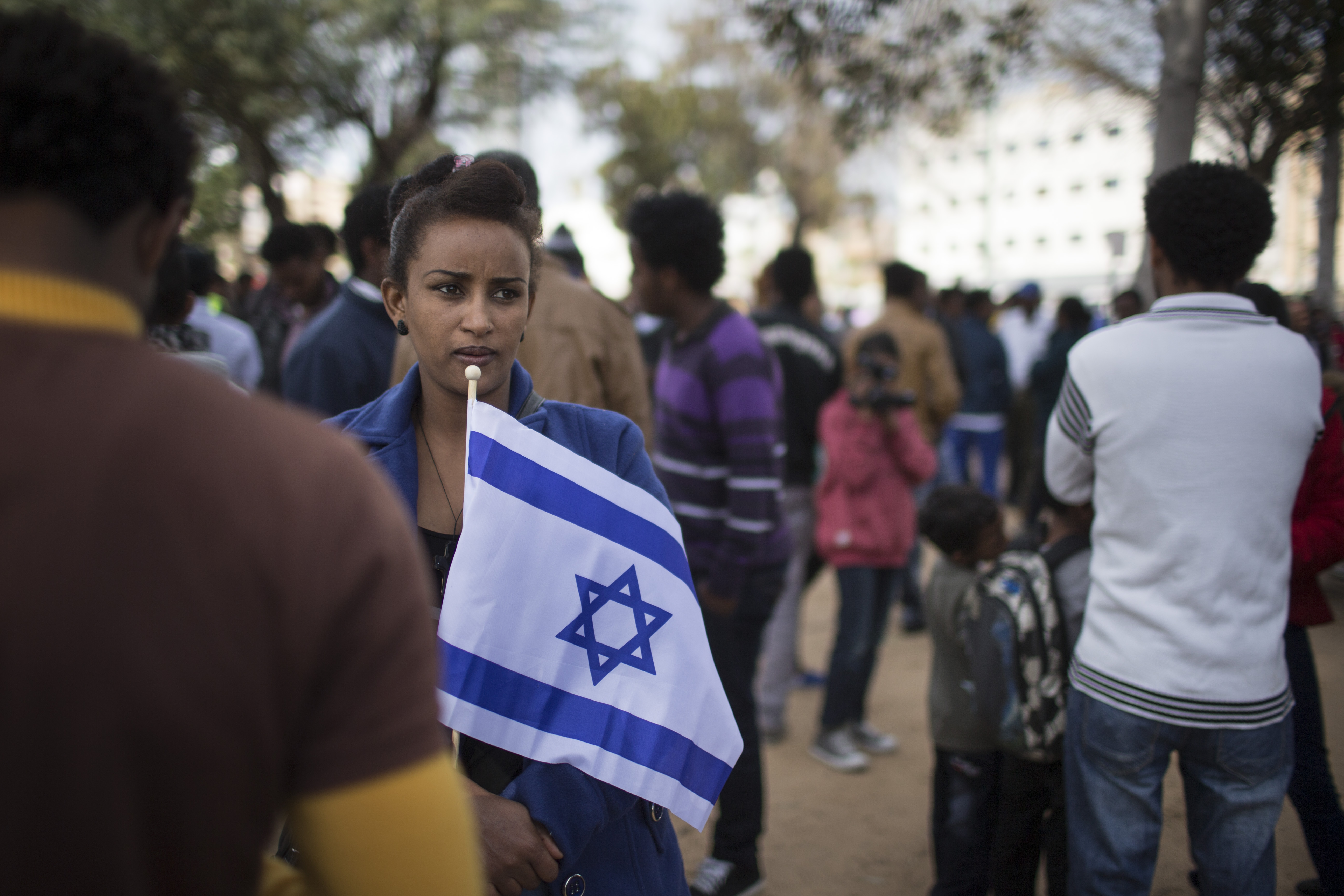 An African woman holds an Israeli flag as thousands of African migrants take part in a rally on January 7, 2014 in Tel Aviv, Israel. Tens of thousands of African asylum seekers are protesting against a law allowing authorities to keep them in open-ended detention until the resolution of their asylum requests are granted, they are deported or they volunteer to leave the country.