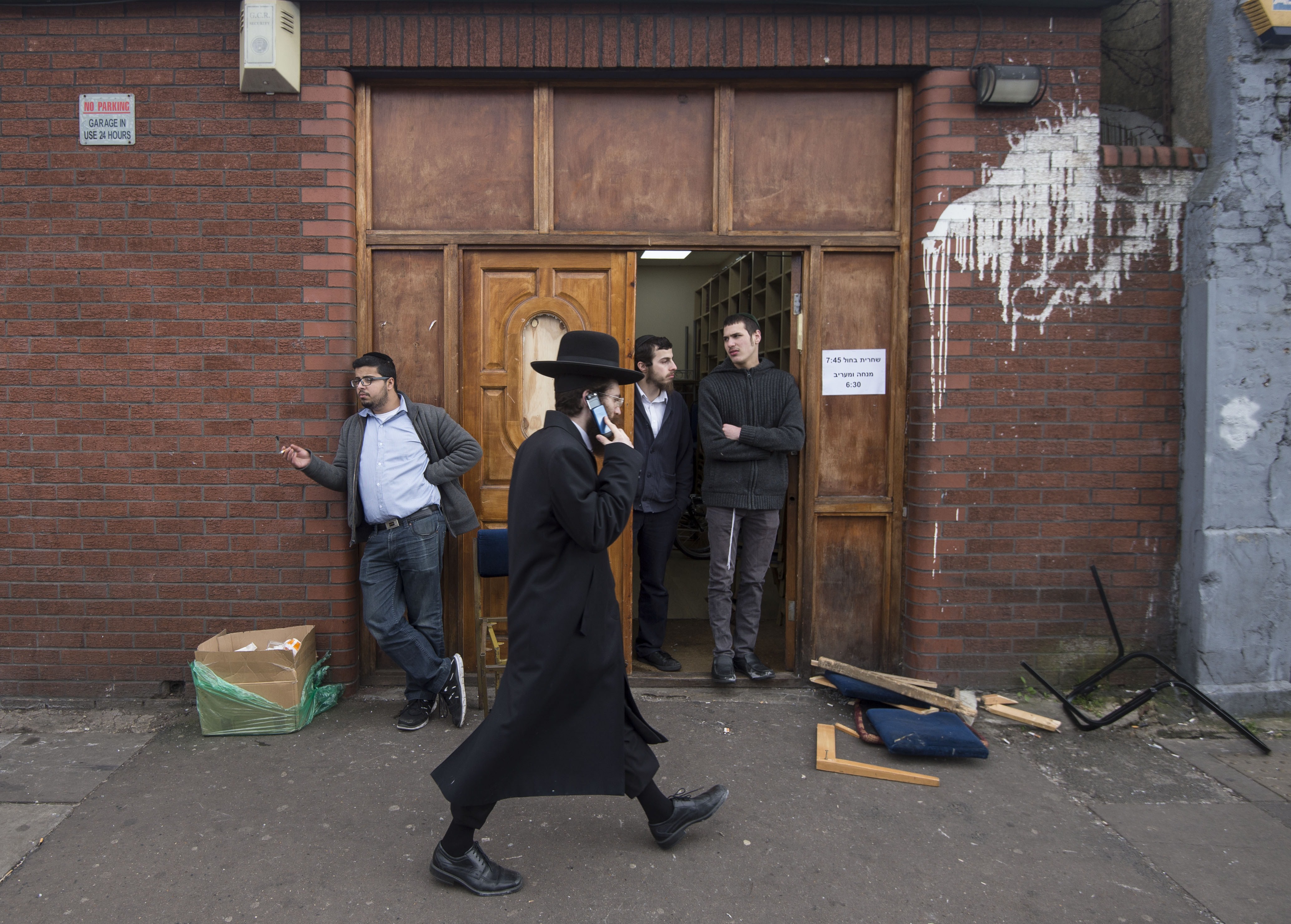 An Orthodox jew talks on his mobile phone as he walks past the Ahavas Torah synagogue in the Stamford Hill area of north London on March 22, 2015. Six people have been arrested after a group broke into a synagogue in a heavily Jewish area of north London, police said Sunday, describing the incident as anti-Semitic. Police were called to the synagogue in Stamford Hill, home to Europe's largest strictly Orthodox Jewish community, in the early hours of Sunday to reports of a disturbance. AFP PHOTO / NIKLAS HALLE'N