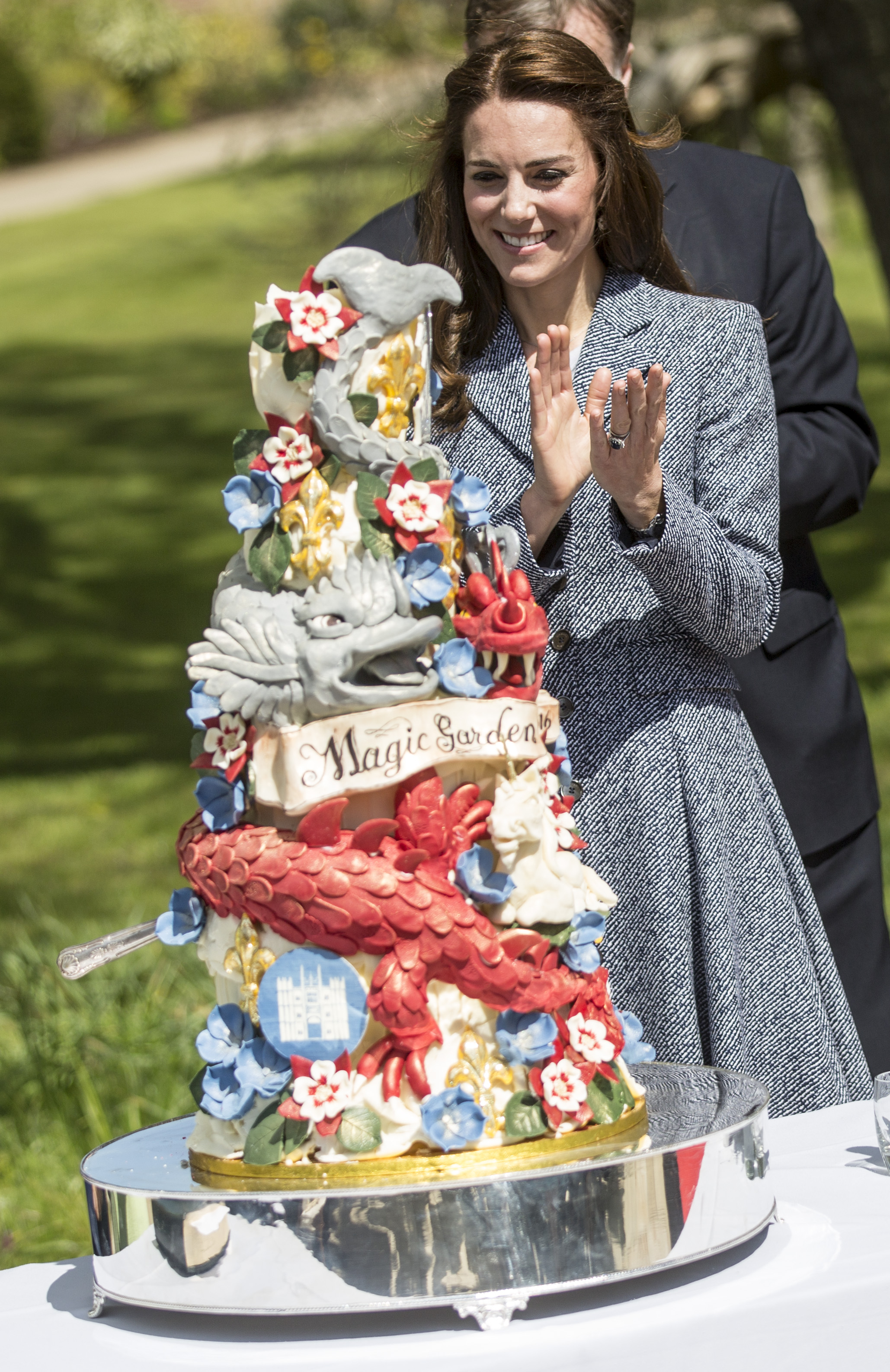 LONDON, ENGLAND - MAY 04: Catherine, Duchess of Cambridge stands next to an ornate cake decorated with dragons and magical creatures baked especially for the opening as she officially opens The Magic Garden at Hampton Court Palace on May 4, 2016 in London, England.